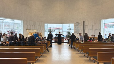 En kirkeindendoms deltagere sidder på bænke, mens præsten står ved alteret