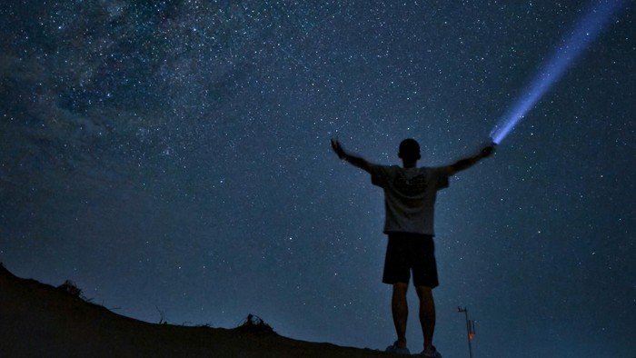 Ein Kind hält eine Taschenlampe. Es ist Nacht.