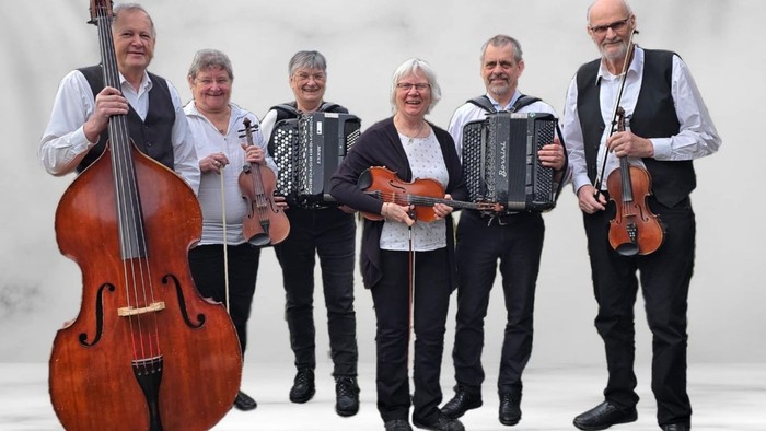 En sekstet poserer med deres musikinstrumenter