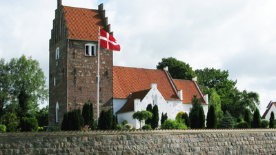 En dansk kirke med flag og murstengevær.