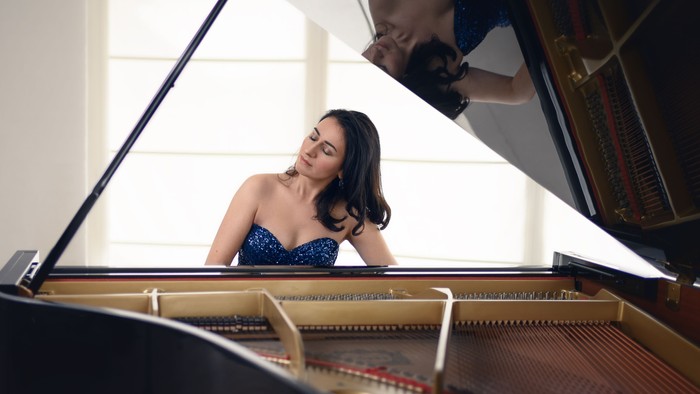 En kvinde spiller piano i et lyset rum.