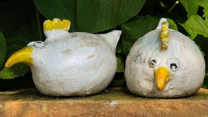 Zwei Keramiktöpfe in Form von Hühnern auf einer Mauer