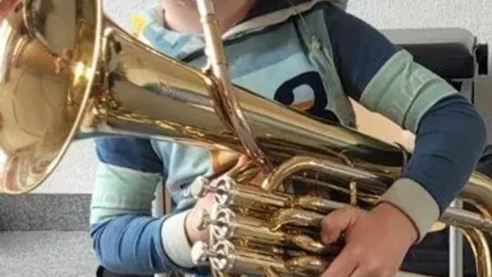 Ein Kind spielt eine Posaune in einem Raum.