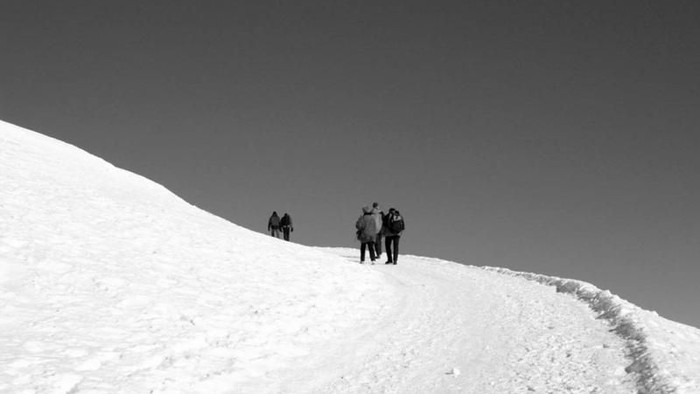 Eine Gruppe von Menschen steigt einen schneebedeckten Hang hinauf