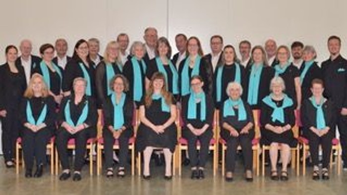 En gruppe af mænd og kvinder i formelle uniformer poserer sammen i en sal.