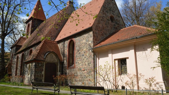 Altes Steinhaus mit rotem Dach und zwei Bänken davor