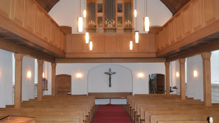 Leere Kirche mit Holzgestühl und roter Teppichbahn