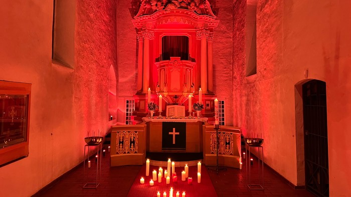 Kirchlicher Altarraum mit Kerzenlicht und Kreuzigungsgruppe