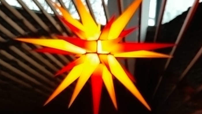 Leuchtende orangefarbene Sterndekoration an der Decke
