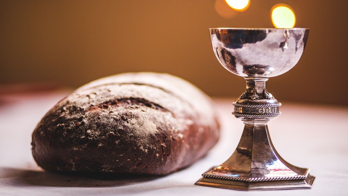 Silver chalice and dark bread on table