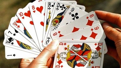 En hånd holder en fanskarven med spillekort.