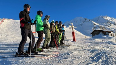 Ein Skilehrer und eine Gruppe Skifahrer auf einem schneebedeckten Berg