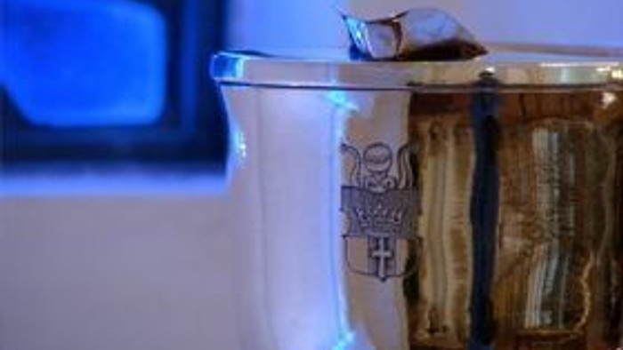 En lille fug sidder på randet af en hvid vase.