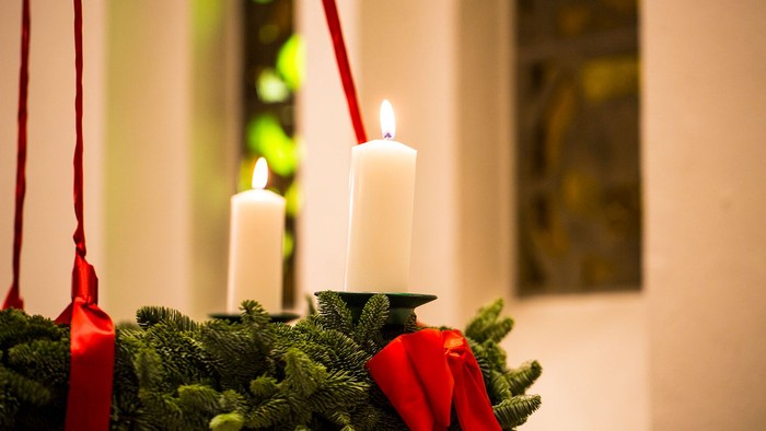 En julekranse med to lysende lysekøn med røde bælter.