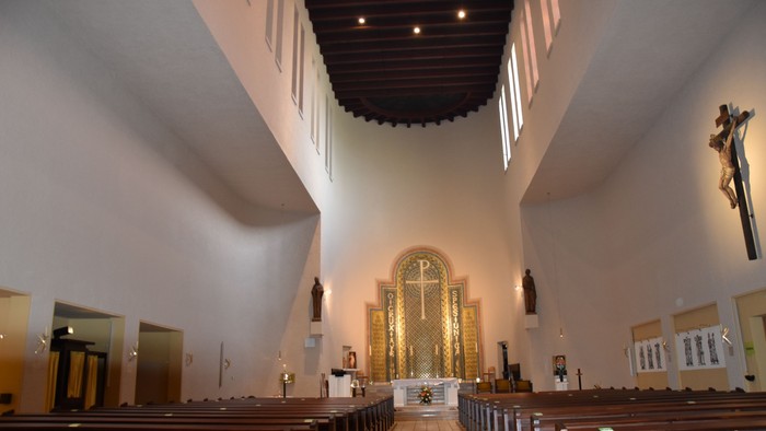 Innenraum einer Kirche mit hölzernen Kirchenbänken und hohem Gewölbedach