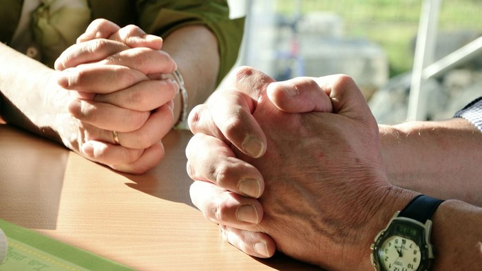 Two people holding hands, one wearing a watch.
