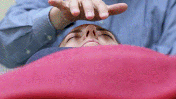 En person ligger på ryggen og holder håndene oppe over ansigtet.