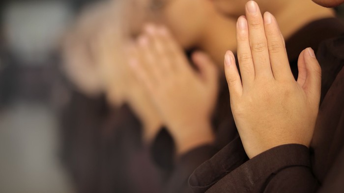 Zwei Personen beten mit gefalteten Händen.