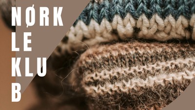 Håndstrikket uldstof med indviklede maskemønstre og "Nørkle Klubb"-tekst overlejret.