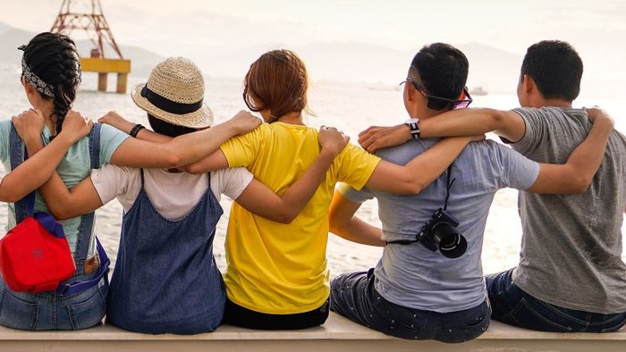 Eine Gruppe von Menschen schaut auf den Sonnenuntergang am Meer.