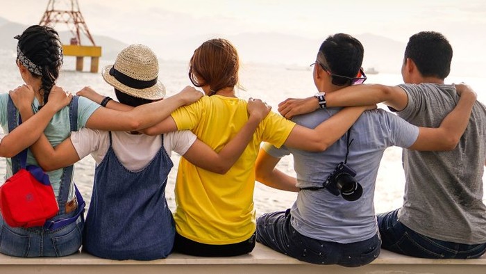 Eine Gruppe von Menschen schaut auf den Sonnenuntergang am Meer.