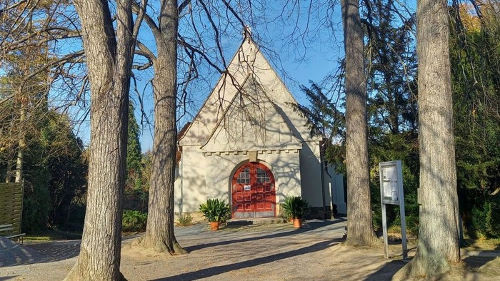 Kleine Kirche mit rotem Tor in parkähnlichem Gebiet
