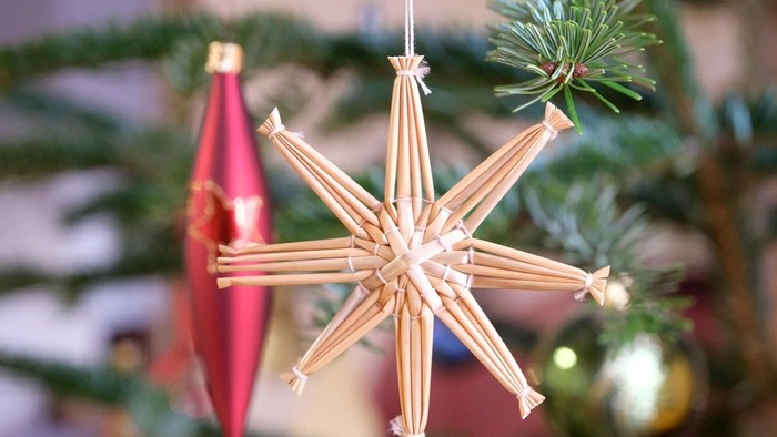 Ein handgefertigter Sternbaumschmuck hängt am Weihnachtsbaum.