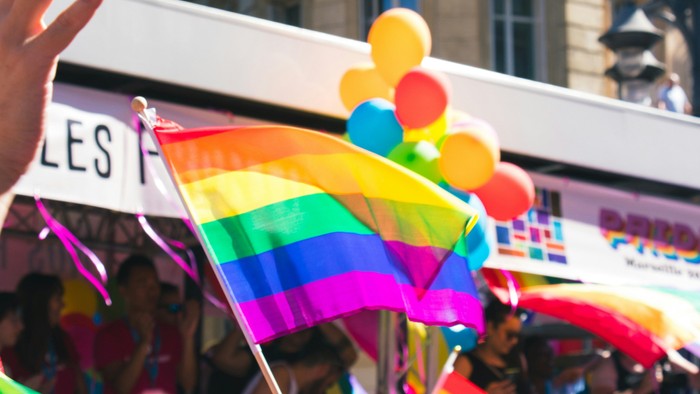Farbenfrohe Parade mit Regenbogenfahnen und Luftballons