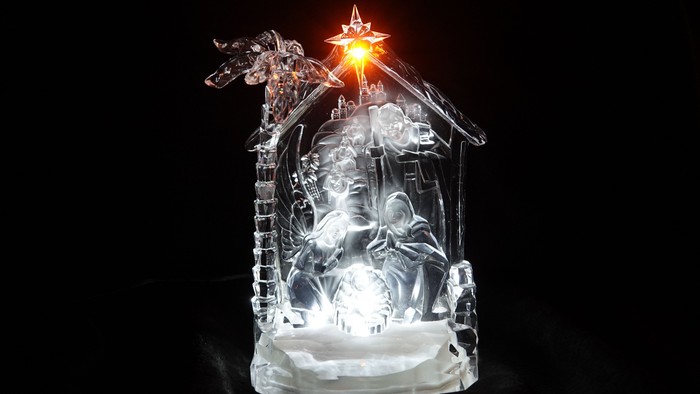 Eine beleuchtete Weihnachtskrippe aus klarem Material mit einer hell leuchtenden Sternenlampe darüber