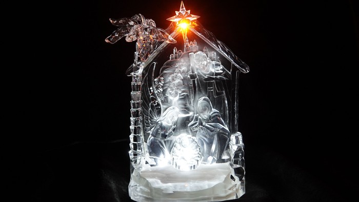 Eine beleuchtete Weihnachtskrippe aus klarem Material mit einer hell leuchtenden Sternenlampe darüber