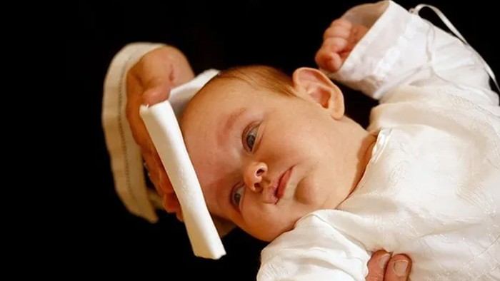 Et spæd barn ligger på ryggen med en stykke papir på hovedet.