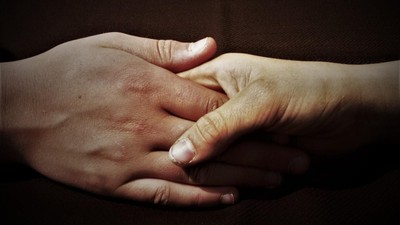 Zwei Hände, die sich halten, mit verschränkten Fingern.