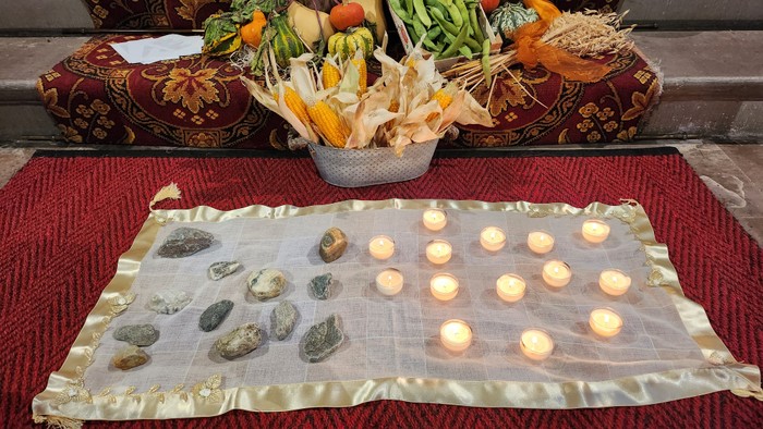 Ein Tisch mit Kerzen, Gemüse und einer goldenen Decke