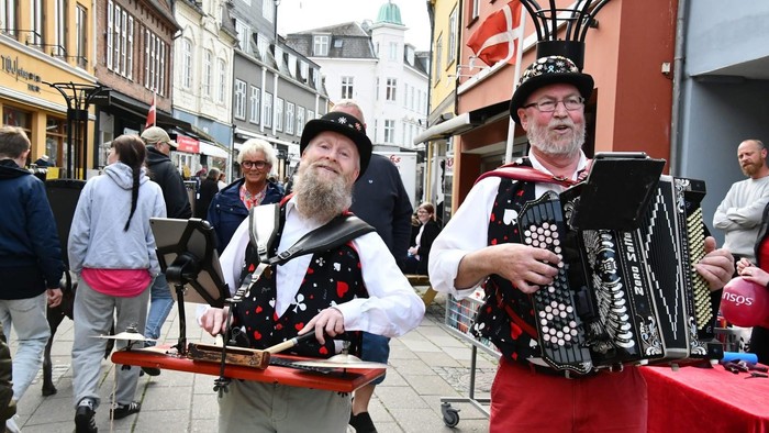 To folkemusikere spiller på gade med instrumenter og bærte farverige kostumer