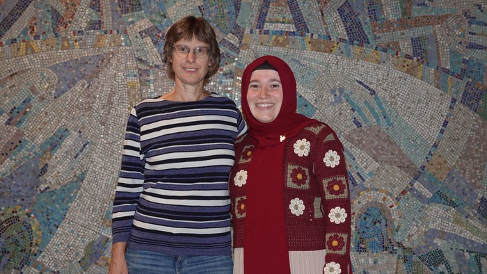 Zwei Frauen stehen vor einer bunten Wand.