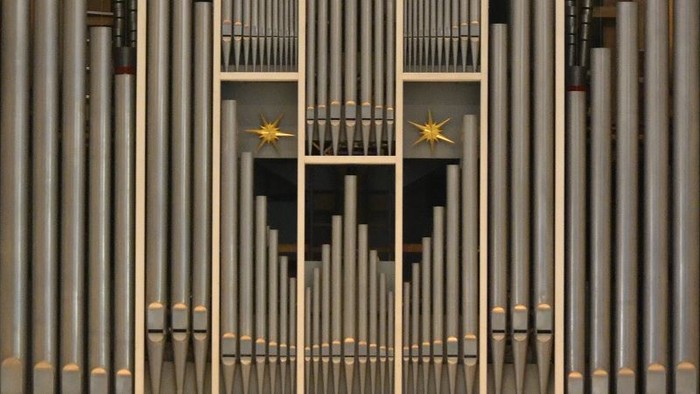 Das Bild zeigt eine Orgel mit zahlreichen Pfeifen und zwei goldenen Sternen.