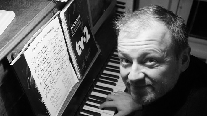 Mand spiller piano og ser nede i partituret