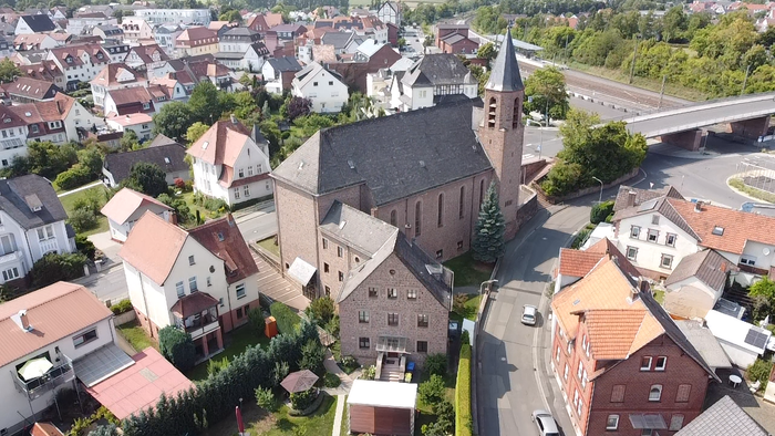Luftaufnahme einer Stadt mit einer markanten Kirche und umliegenden Häusern.