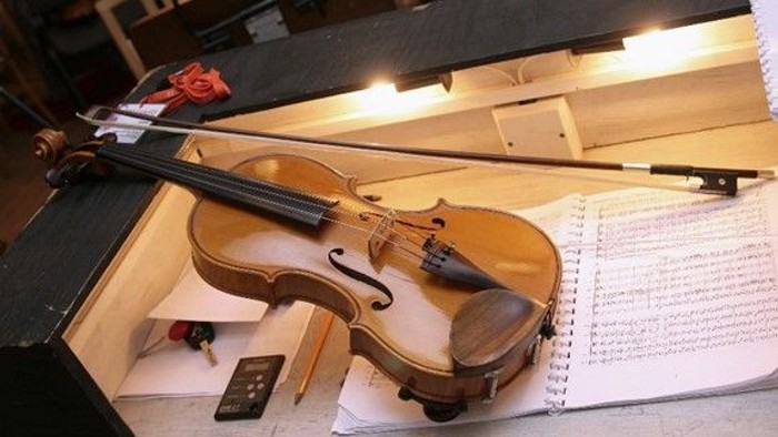 Geige auf Notenbuch mit Handy und Stift