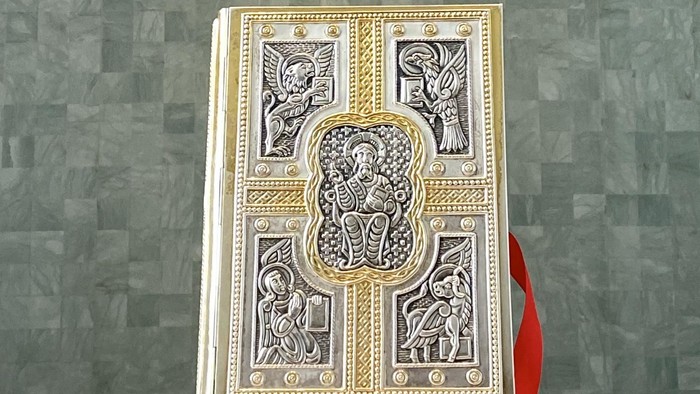 Aufwendiges Altarretabel mit religiösen Schnitzereien und einem verhüllten Kreuz vor einem grün gefliesten Hintergrund.