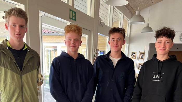 Fire drenge står sammen i et lokal.