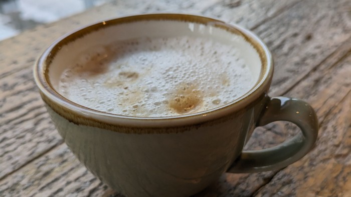 Eine Tasse Cappuccino auf einem Holztisch.
