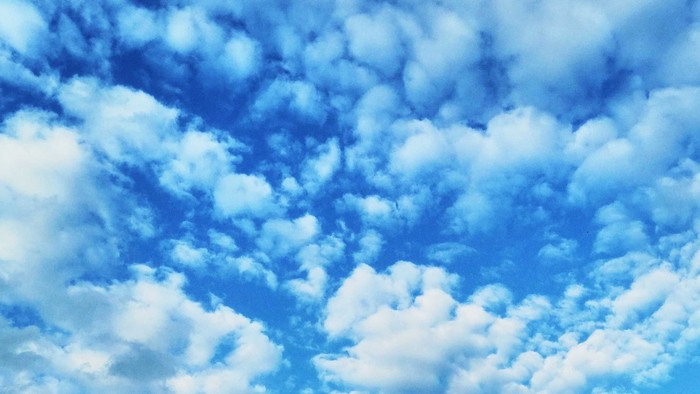 Flauschige weiße Wolken verstreut am hellblauen Himmel