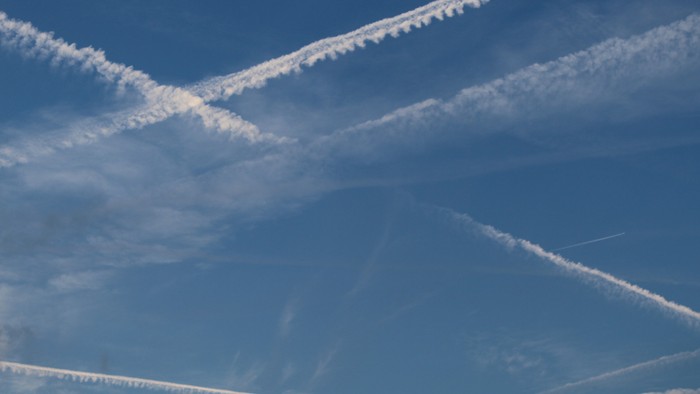 Weiße Kondensstreifen durchziehen den blauen Himmel.