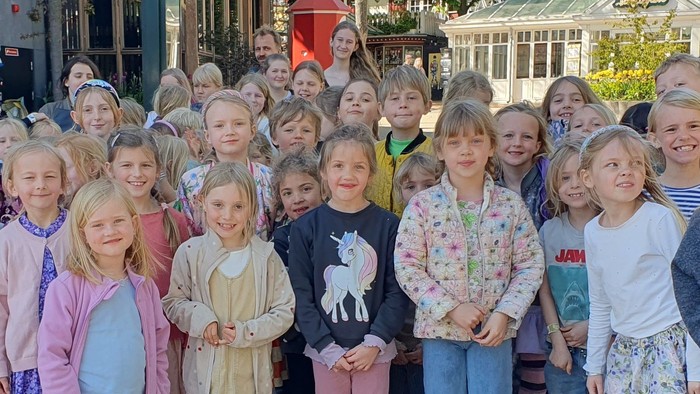 En gruppe børn og voksne poserer sammen på en gade