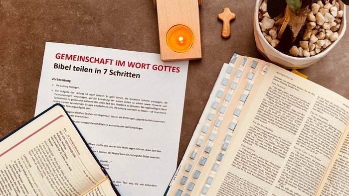 Religiöse Studienmaterialien, darunter eine Bibel, Leitfäden, eine Kerze und eine kleine Topfpflanze auf einem Tisch.