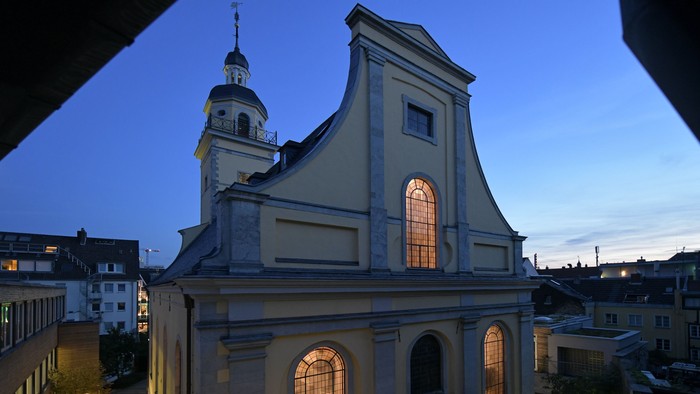 Ein weißer Kirchenbau mit beleuchteten Fenstern bei Dämmerung