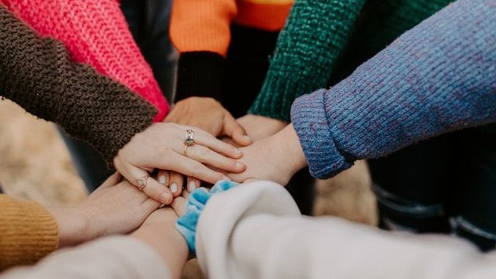 Eine Gruppe von Menschen hält sich an den Händen, um ihre Einheit zu symbolisieren.