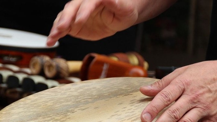 Eine Person spielt ein traditionelles Musikinstrument, möglicherweise eine Trommel oder ein Xylophon.