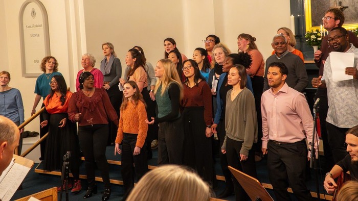 En gruppe af mennesker står sammen og synger i en kirke.